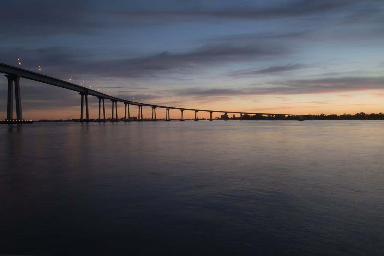 Coronado Bridge at sunset overlooking San Diego Bay, highlighting Coronado's luxury real estate market, presented by Amy Ali, Agency West.