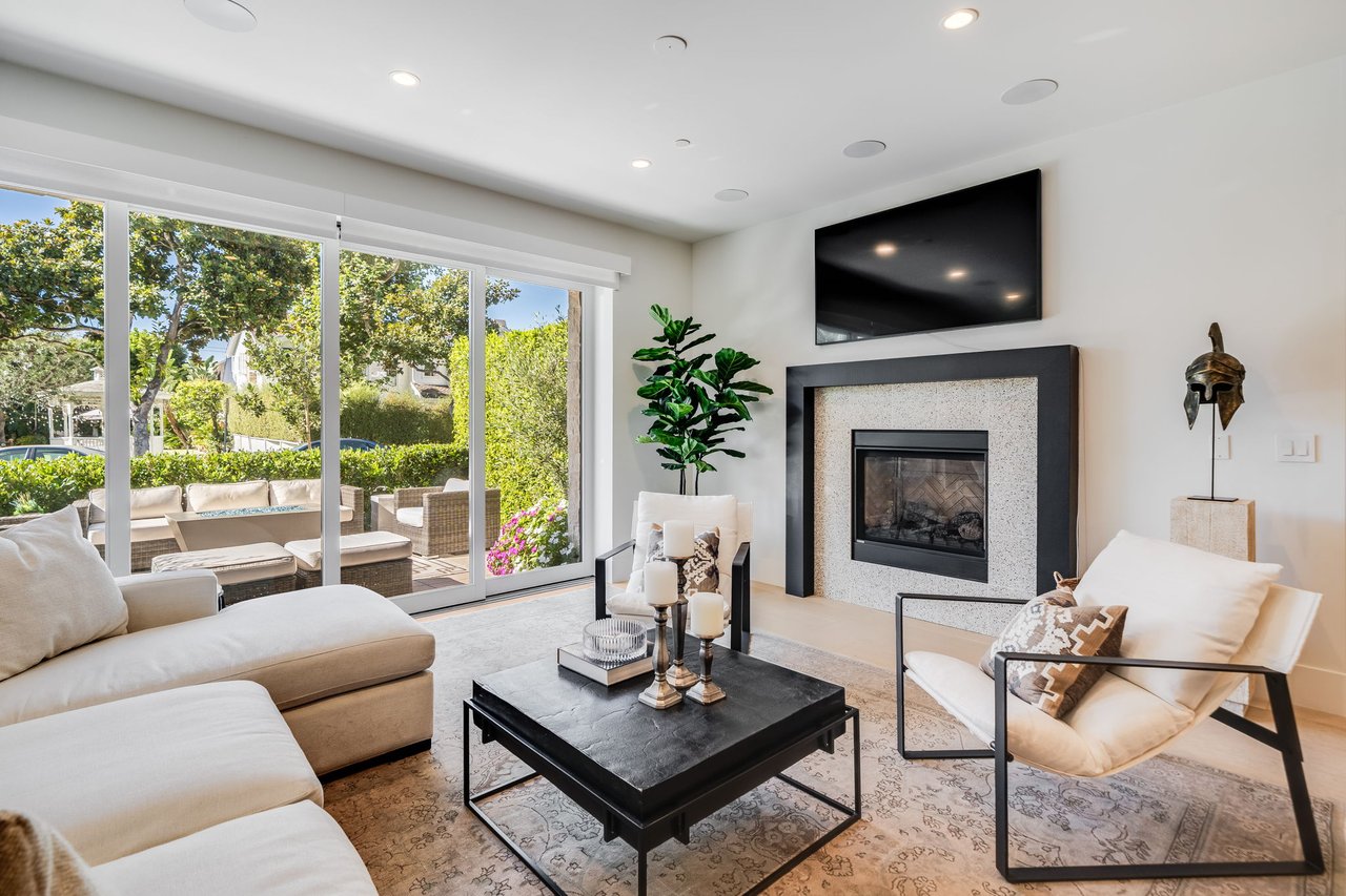 Furnished living room with a modern fireplace and sliding doors opening to a landscaped patio.