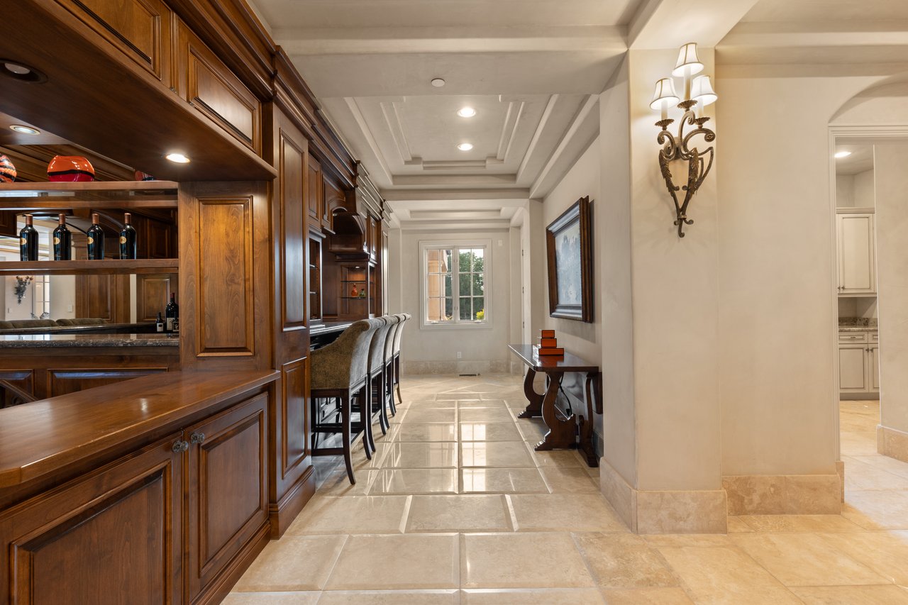 Built-in wood bar with stools along a tiled hallway, with a window at the far end.