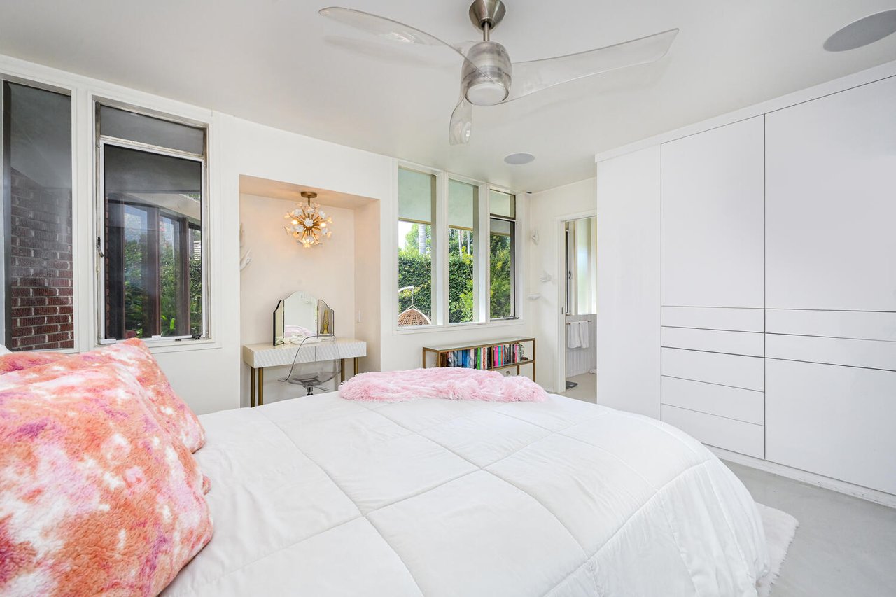 Bright mid-century bedroom in The Plaza Long Beach with large windows, built-in storage, and garden views