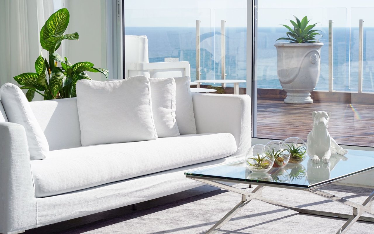 Elegant coastal living room with white sofa, glass coffee table, and ocean view in Naples FL condo