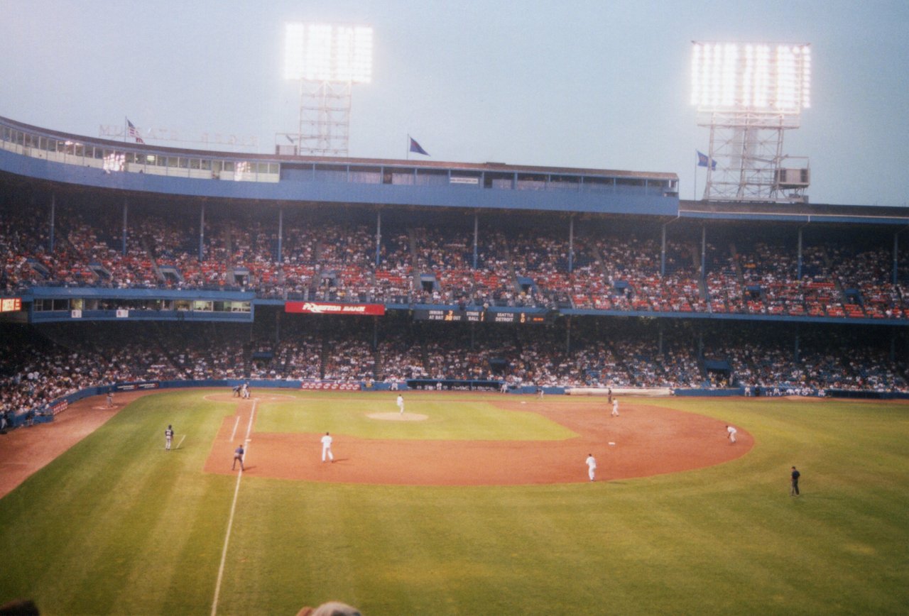 Baseball game at Tiger Stadium, with crowded blue grandstands and bright floodlights.