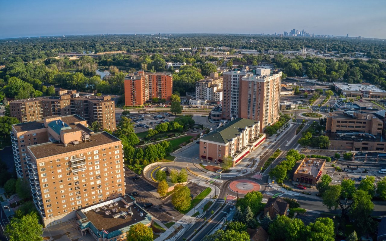 Aerial view of Richfield buildings and tree-lined streets, with the Minneapolis skyline in the distance.
