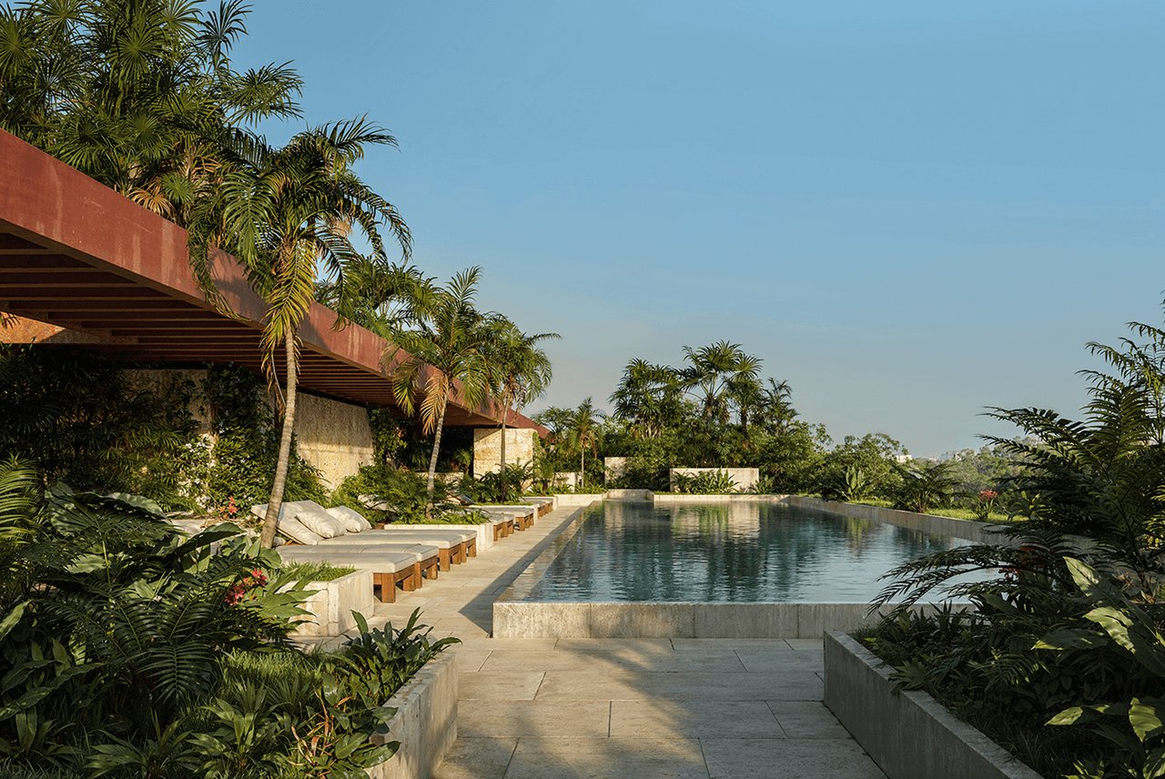 Swimming pool with cushioned loungers, tropical palms, and a modern terracotta-colored overhang.