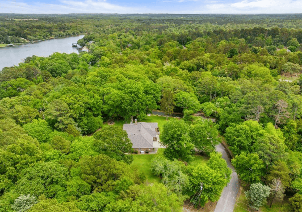 Aerial view of a home on a heavily wooded acre-plus lot adjacent to Lake Palestine in Cumberland Ridge neighborhood, Bullard, TX