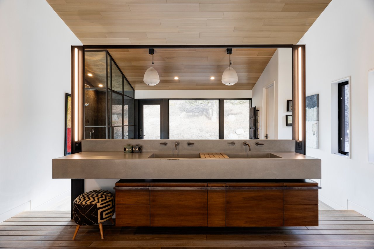 Luxury Boulder bathroom with floating concrete double vanity, wood storage, and geometric patterned ottoman