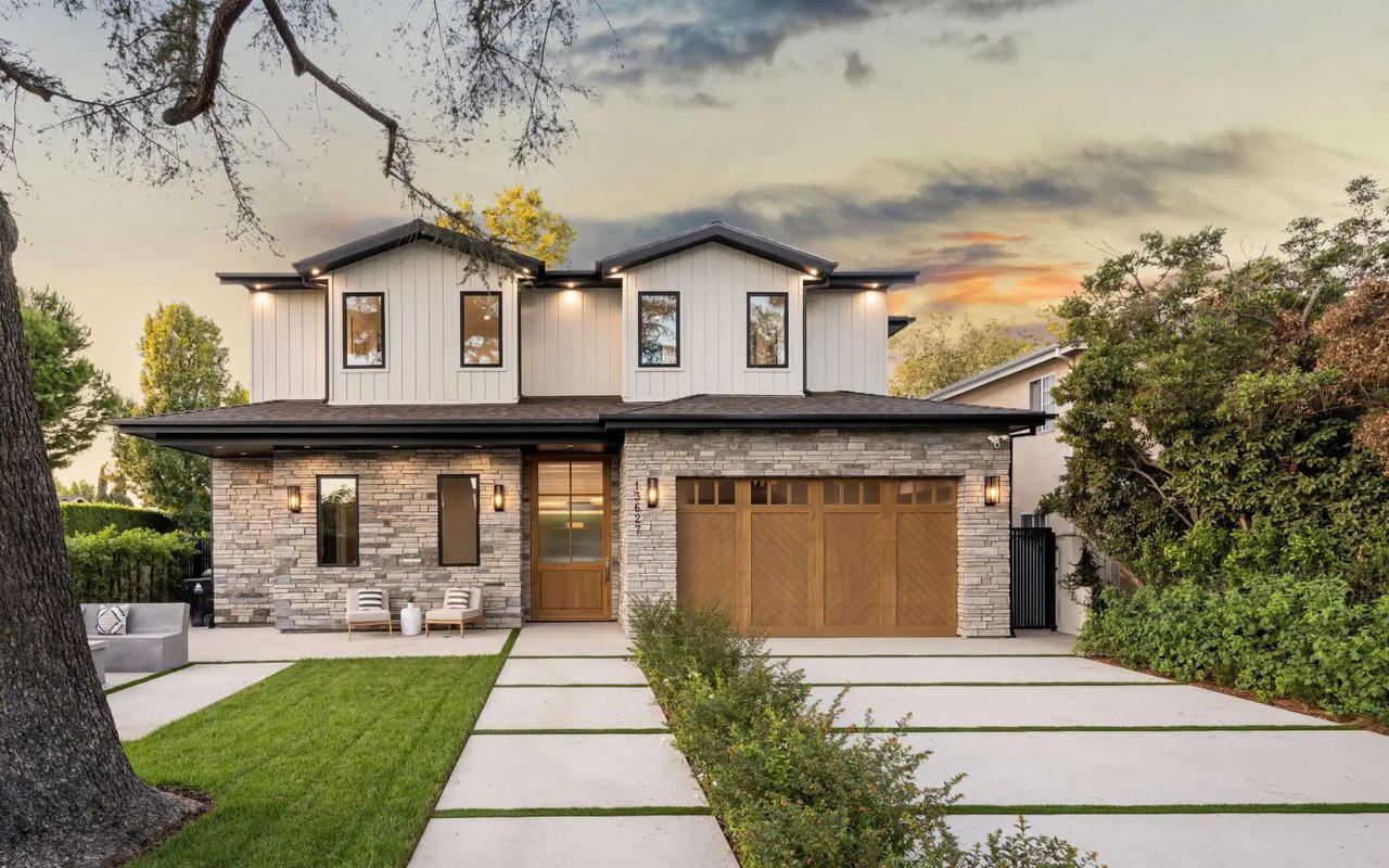 Modern two-story home with stone and wood exterior at sunset, showing the front yard and driveway.