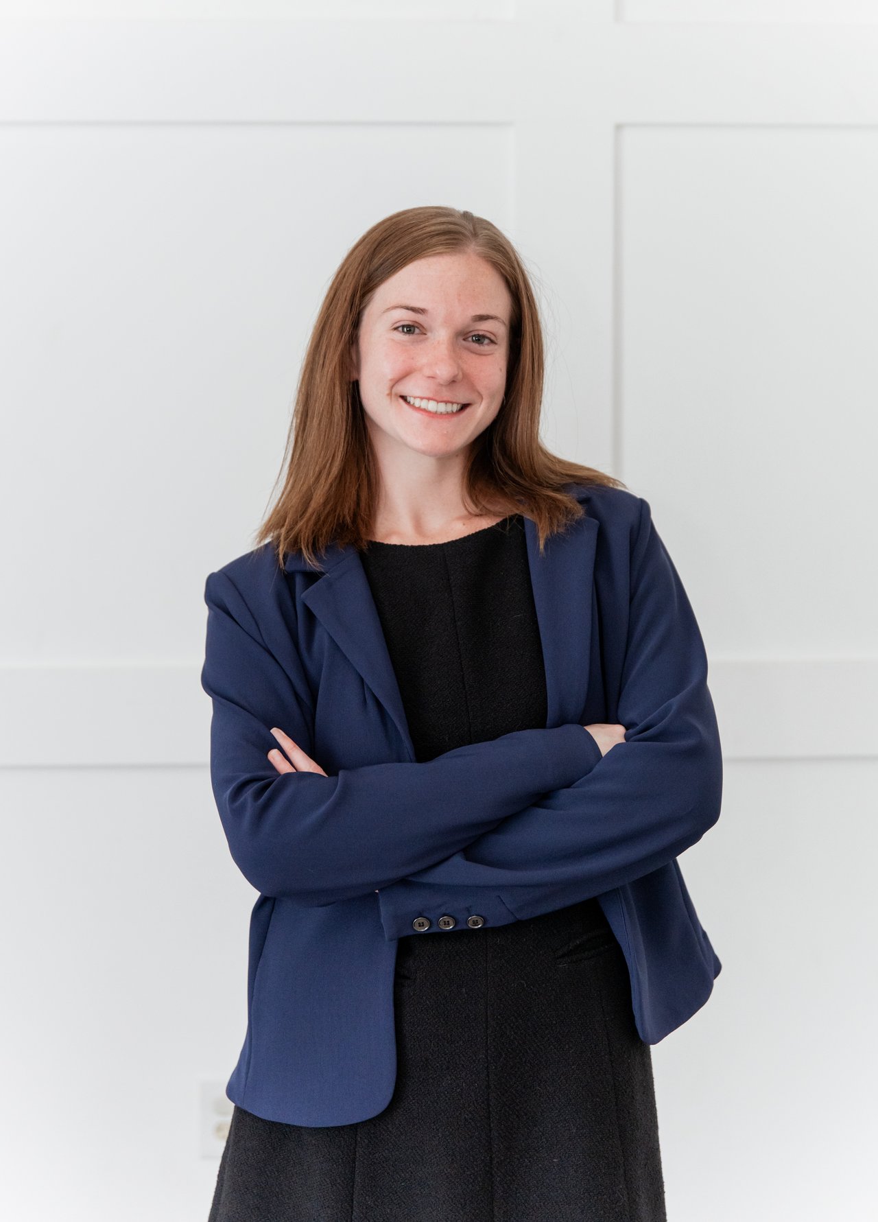 Sydney Ballance in a navy blazer, smiling with her arms crossed.