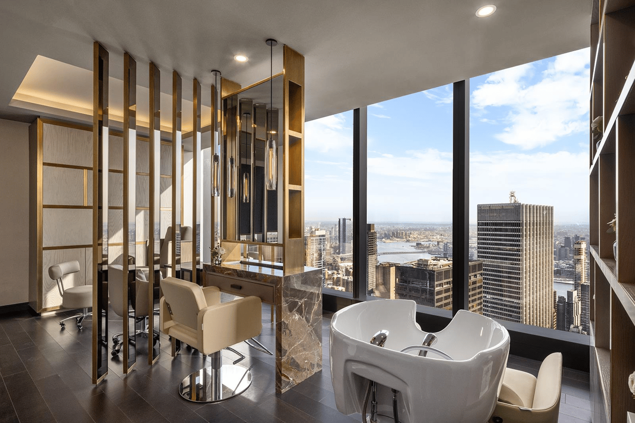 Salon with styling chairs and mirrors beside floor-to-ceiling windows overlooking the city and river.