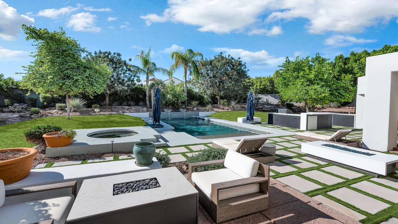 Backyard pool and circular spa beside a modern paved patio with cushioned seating.