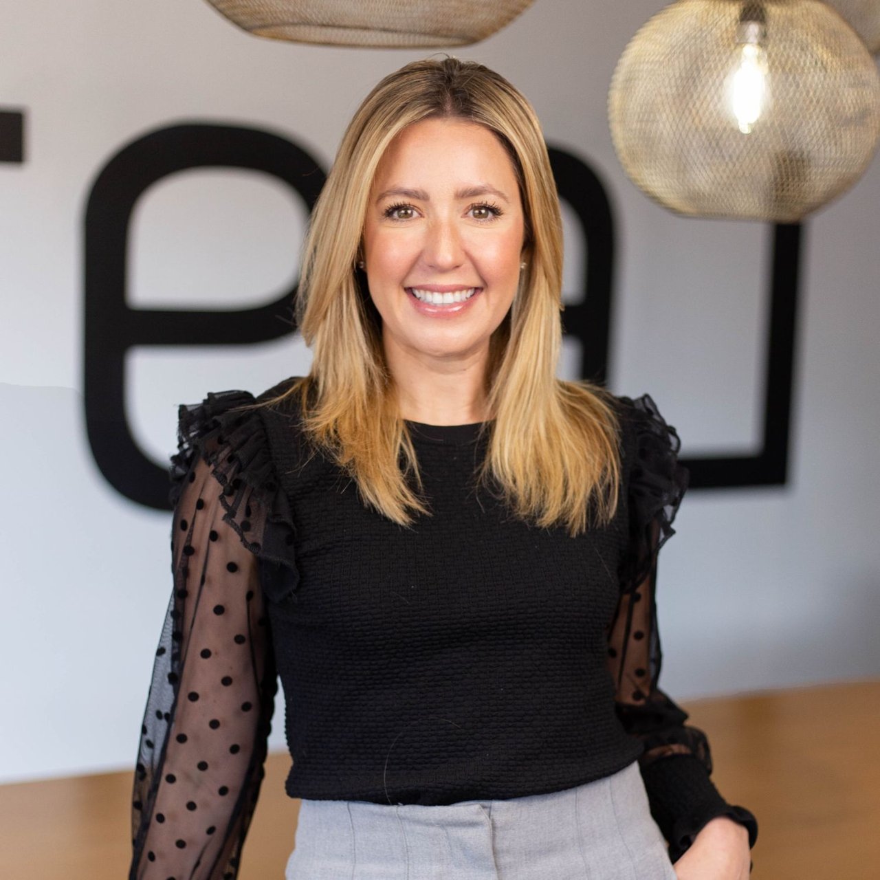 Melissa Chernetsky smiling in a black blouse with sheer polka-dot sleeves.