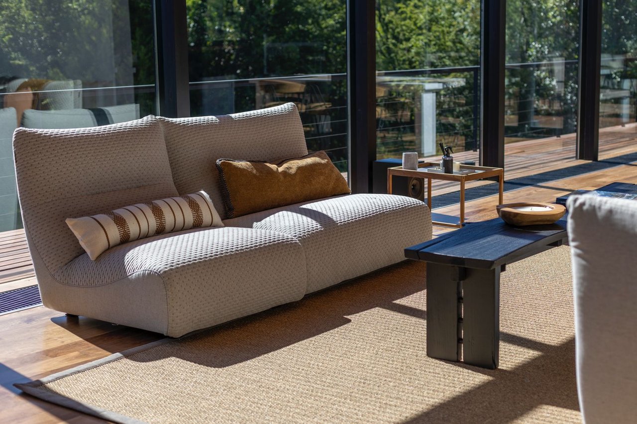Living room with a cream sofa and dark coffee table beside floor-to-ceiling windows.