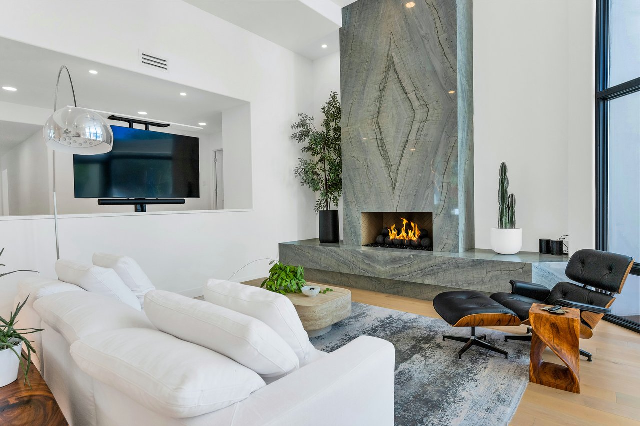 Living room with a dramatic veined stone fireplace, white sectional, and large windows.