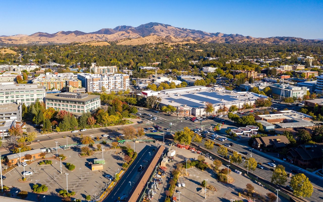 Aerial view of a town and tree-lined neighborhoods, with dry mountains in the background.
