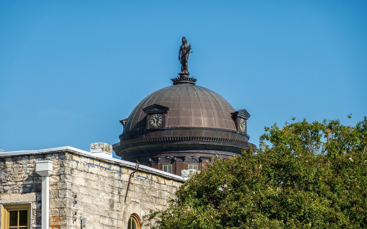 Williamson County Courthouse dome and statue rising above trees in Georgetown, Texas.