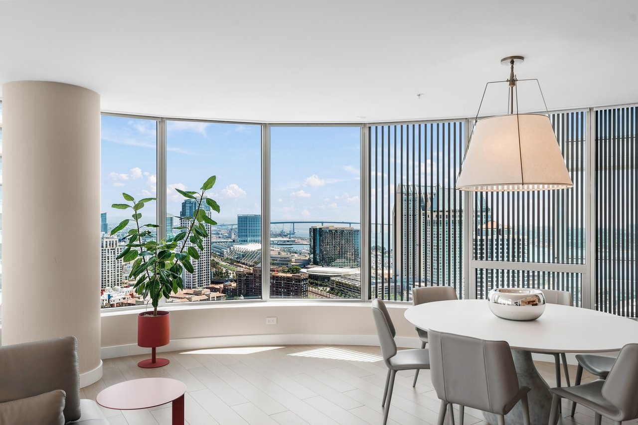Dining area with a round white table and chairs overlooking downtown San Diego and the bay.