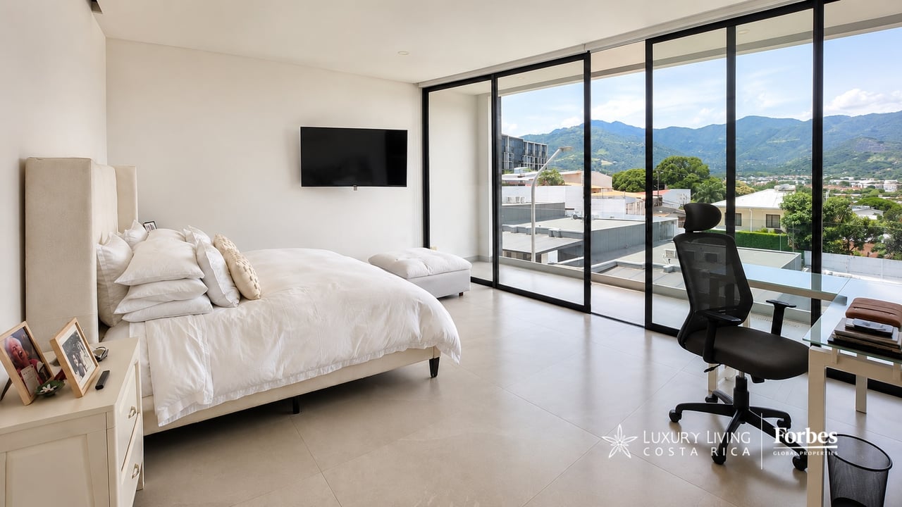 Contemporary bedroom with glass doors framing mountain views and a balcony.