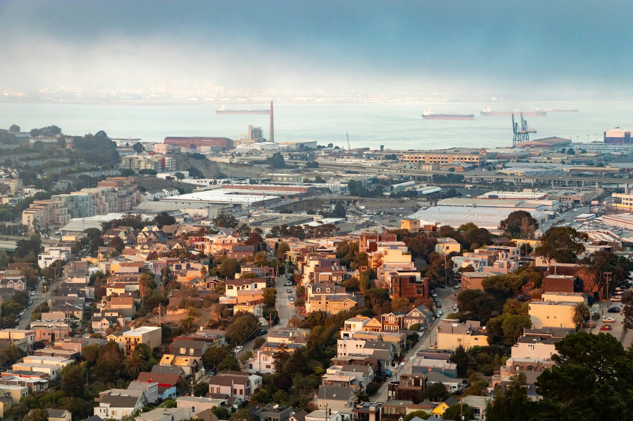 Aerial view of Bernal Heights in San Francisco, showcasing hillside homes, winding streets, and the greenery of Bernal Heights Park with panoramic city views in the background.
