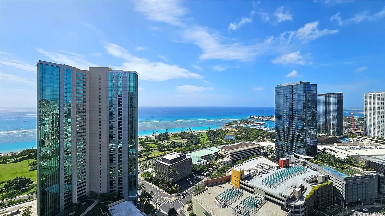Honolulu waterfront and ocean viewed from above, with high-rises in the foreground.