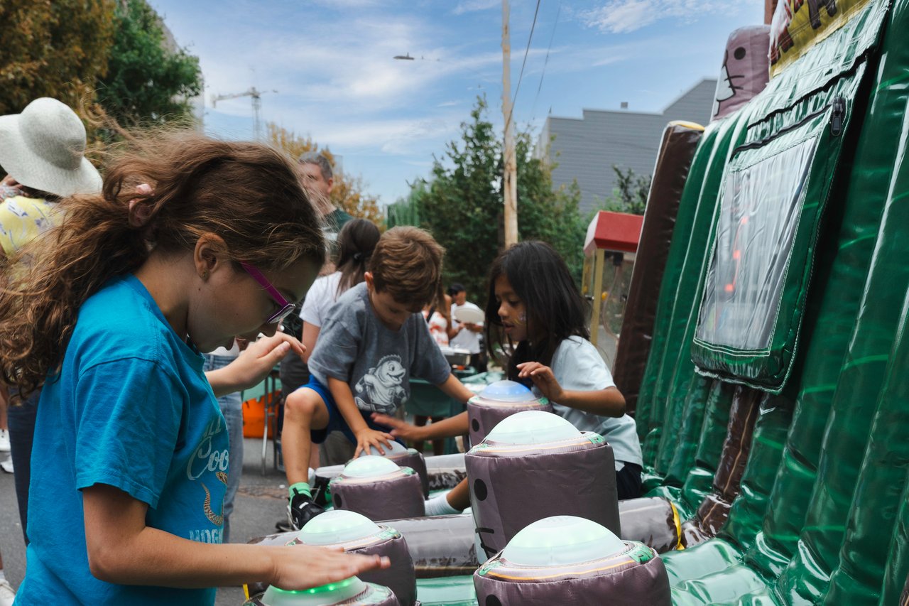 Children play an inflatable arcade game at an outdoor neighborhood block party.