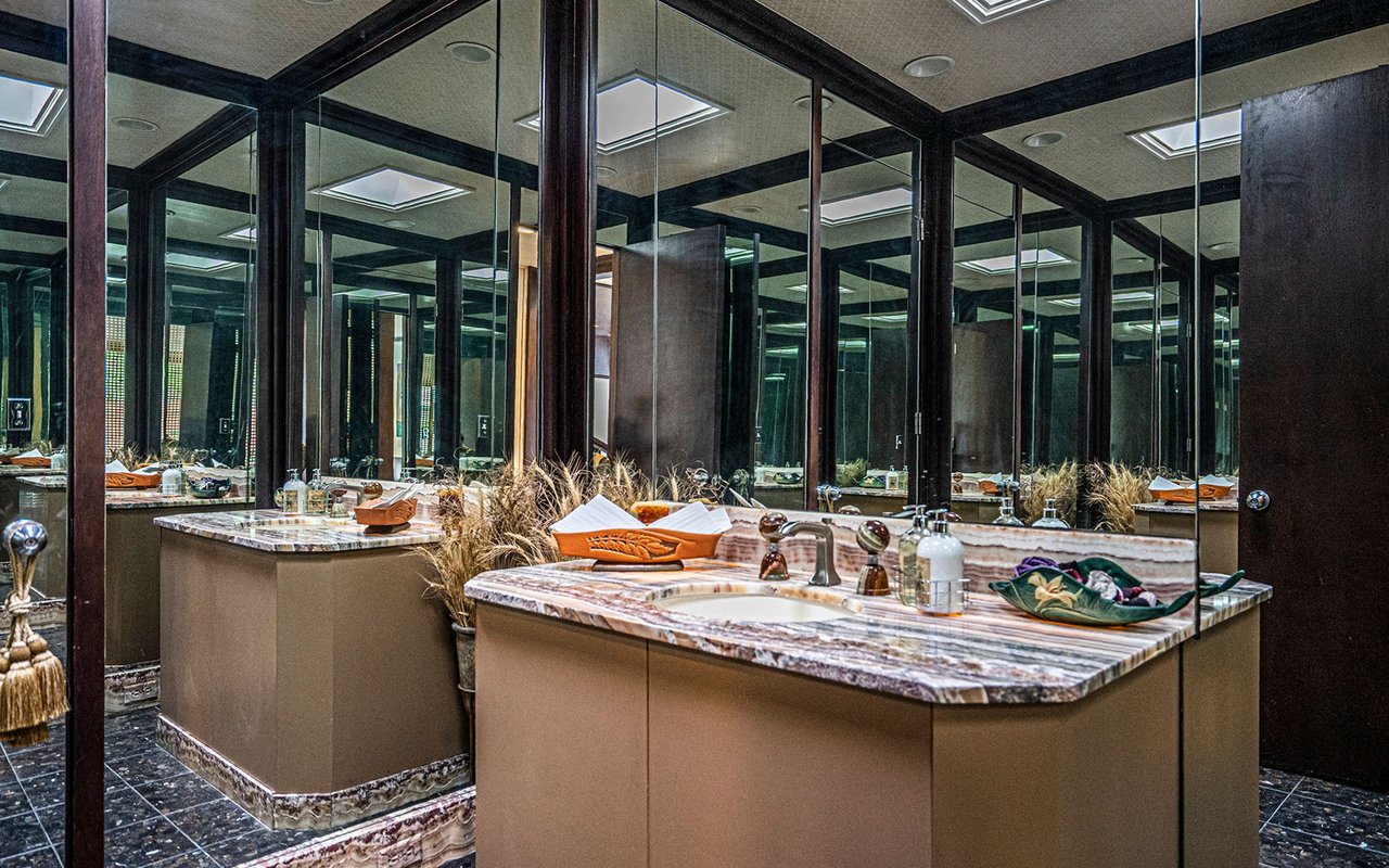 Bathroom vanity with marble counters, two sinks, and mirrored walls.