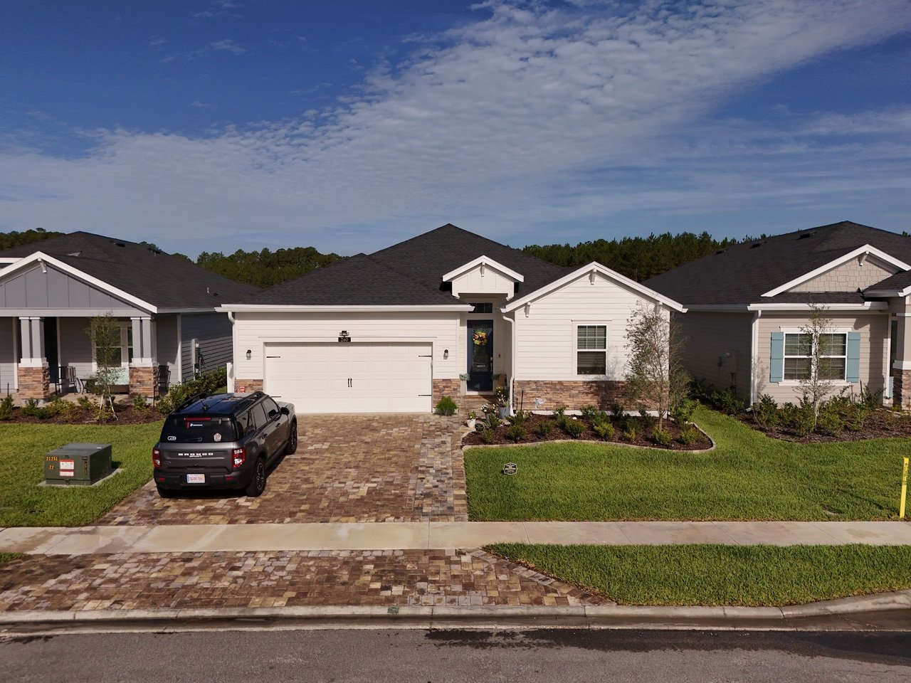 Single-story home with a two-car garage, stone accents, and a paver driveway.