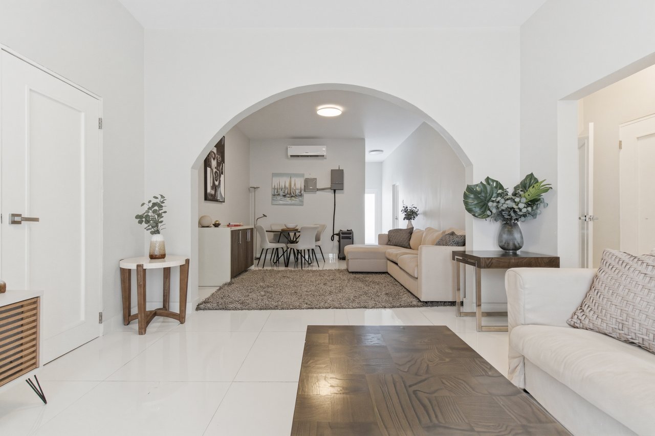 Furnished living room with a large archway, cream sectional, and dining area.