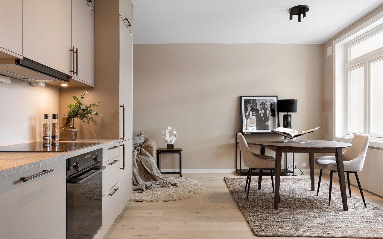 Staged kitchen and dining area with pale cabinetry, a round table, and large windows.
