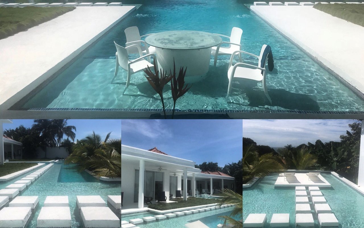 Outdoor pool with white stepping stones and a round table with chairs set in the water.