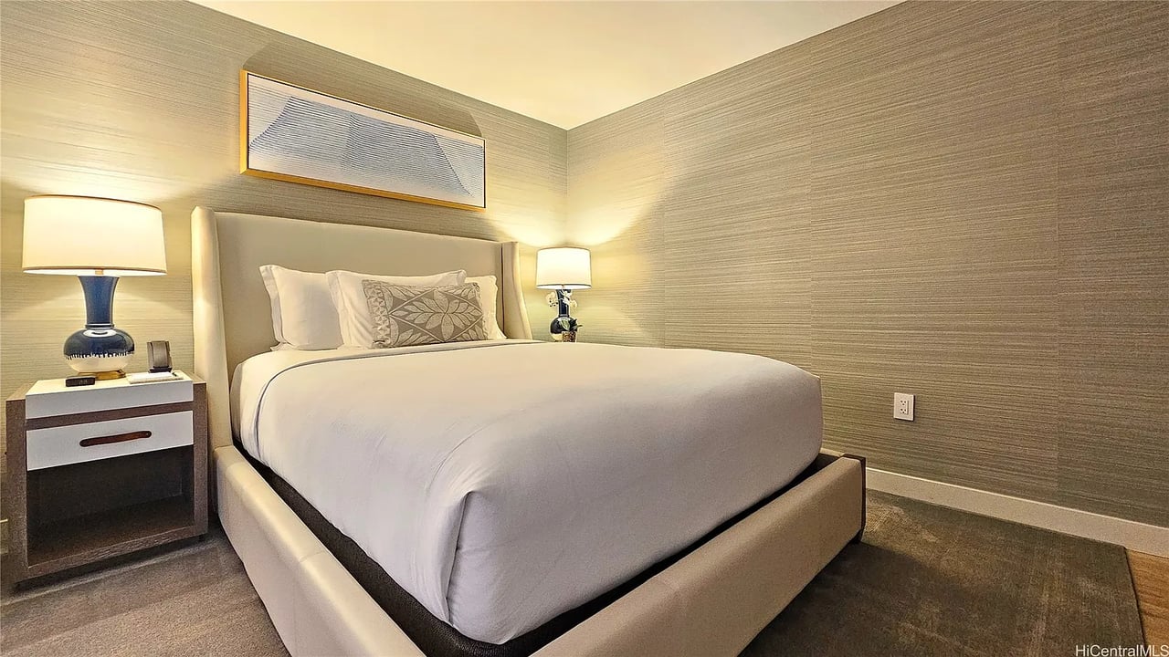 Bedroom with a large white bed, upholstered headboard, and matching bedside lamps.