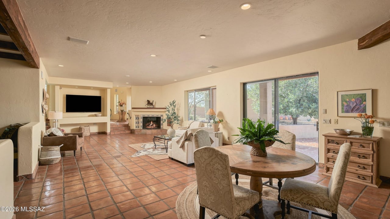 Open-plan living and dining room with terracotta tile floors, tiled fireplace, and sliding glass doors to a patio.