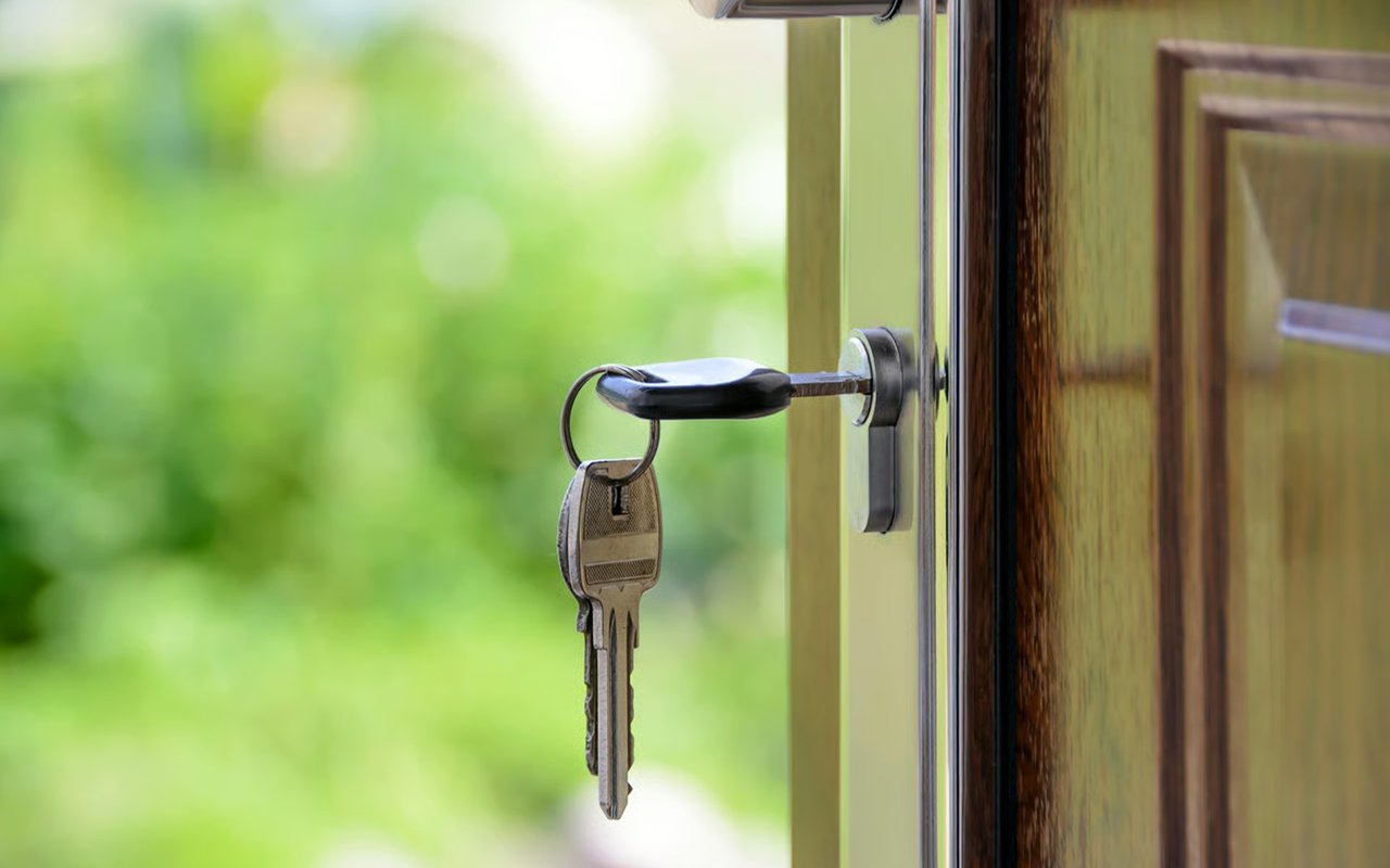 A key inserted in a door lock, with another key hanging from the ring.