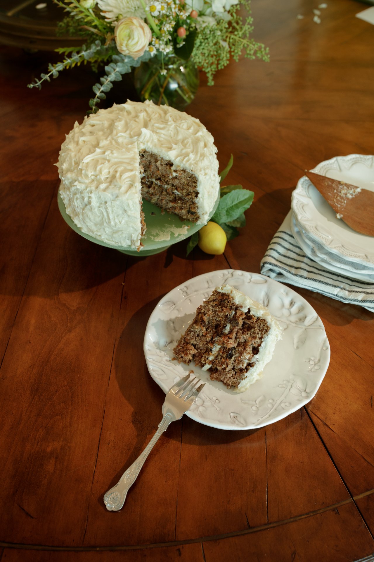 Two-layer carrot cake with cream cheese frosting, flecks of carrot and pineapple visible in the crumb.