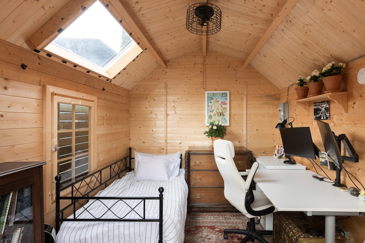 Light-filled detached wooden studio with seating and skylight, perfect for remote work or creative space.