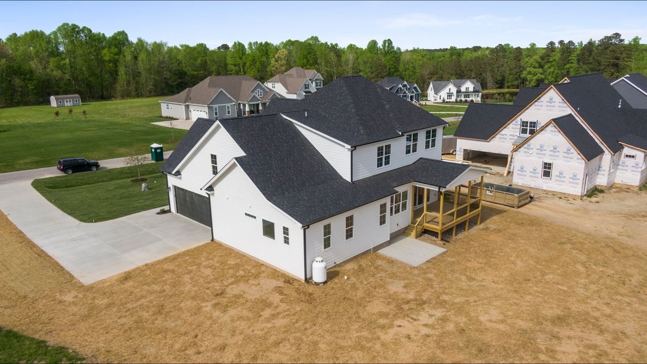 Aerial view of new two-story homes and houses under construction in a wooded suburban neighborhood, like the newer communities in Evans and Columbia County