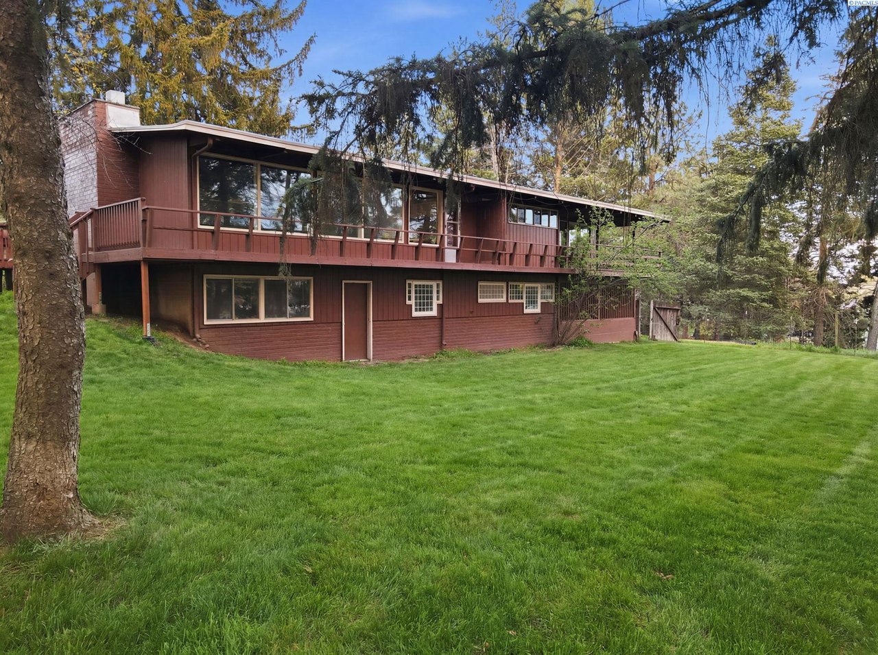 Acreage home at 312 State Route 27 in Pullman WA with a mid-century residence, wooded yard, fenced ground, and horse barn on 2 acres.