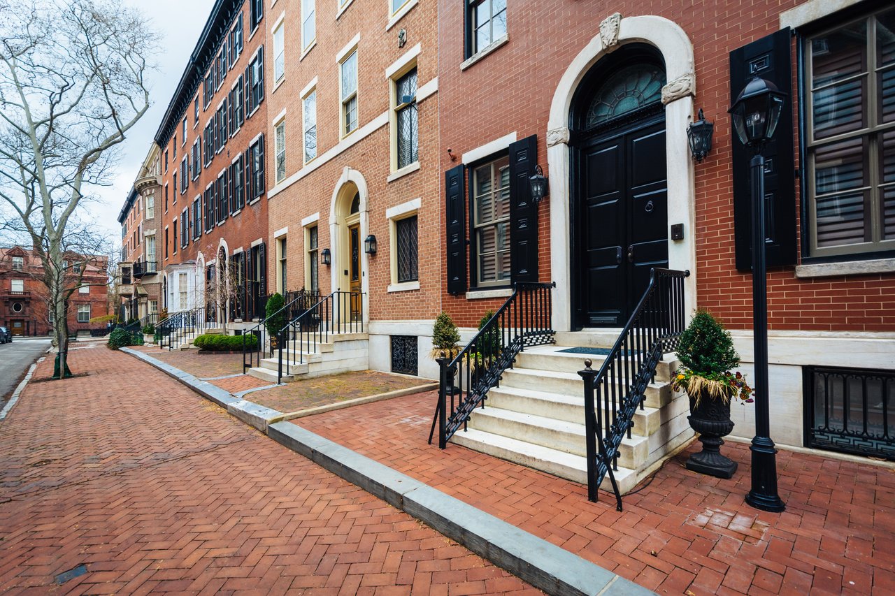 Rittenhouse rowhouses with brick sidewalks, raised stoops, and black iron railings.
