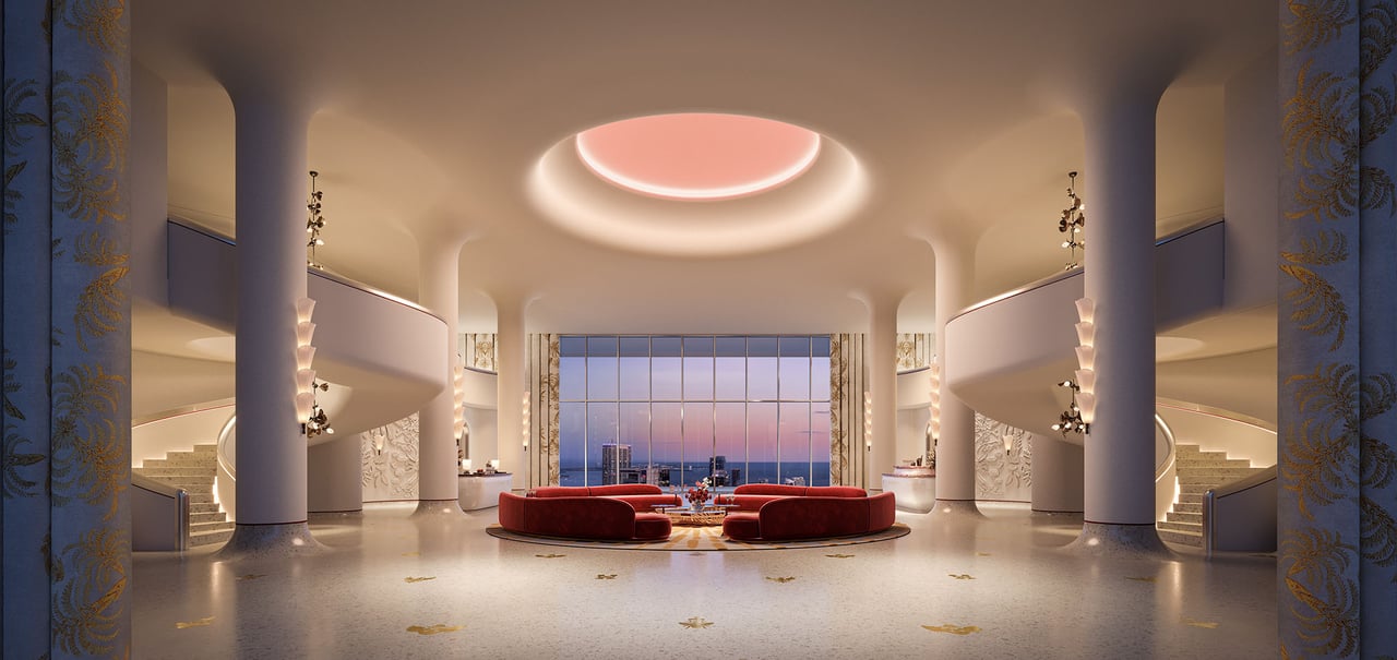 Grand residential lobby with curved staircases, red lounge seating, and a city-and-water view at dusk.