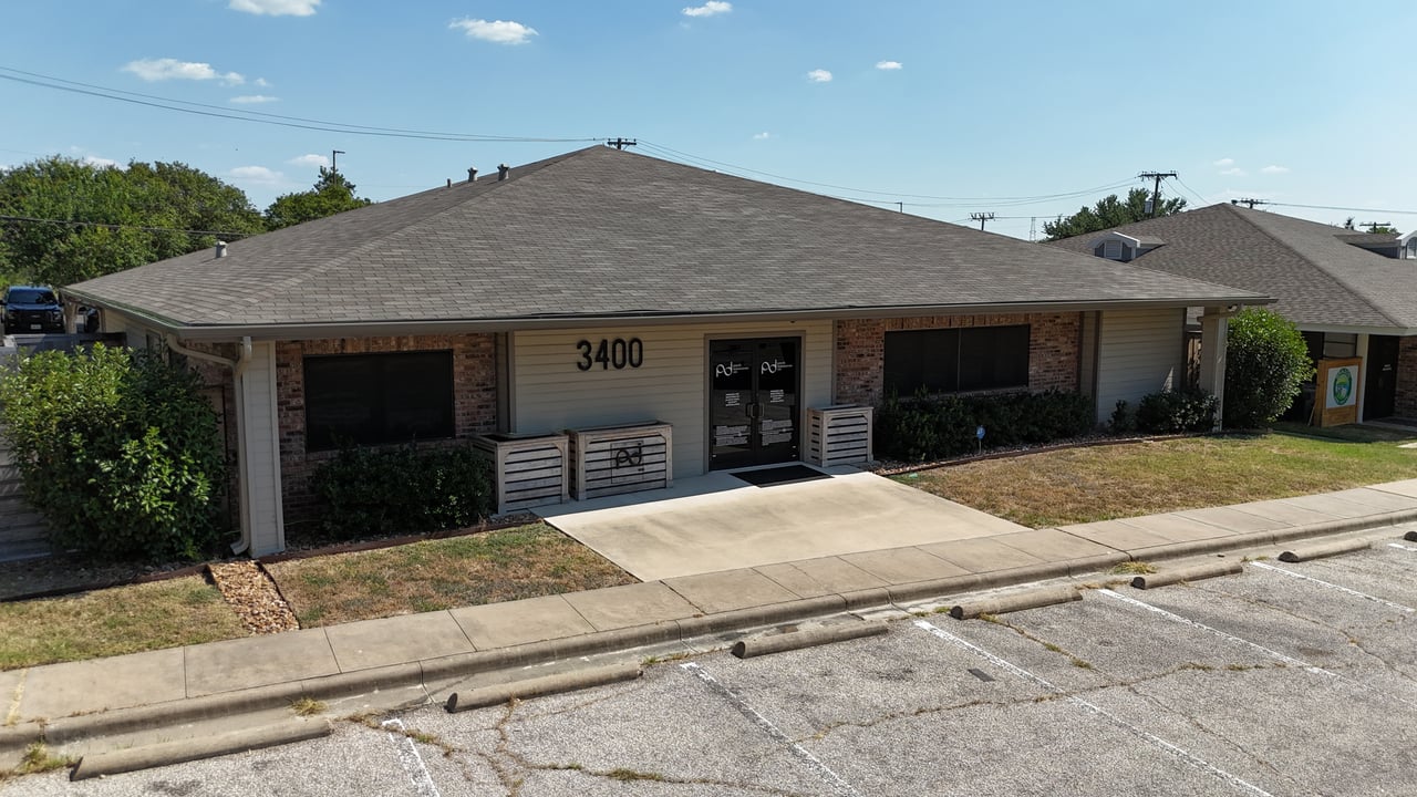 Commercial office building numbered 3400, with a central entrance and parking spaces in front.