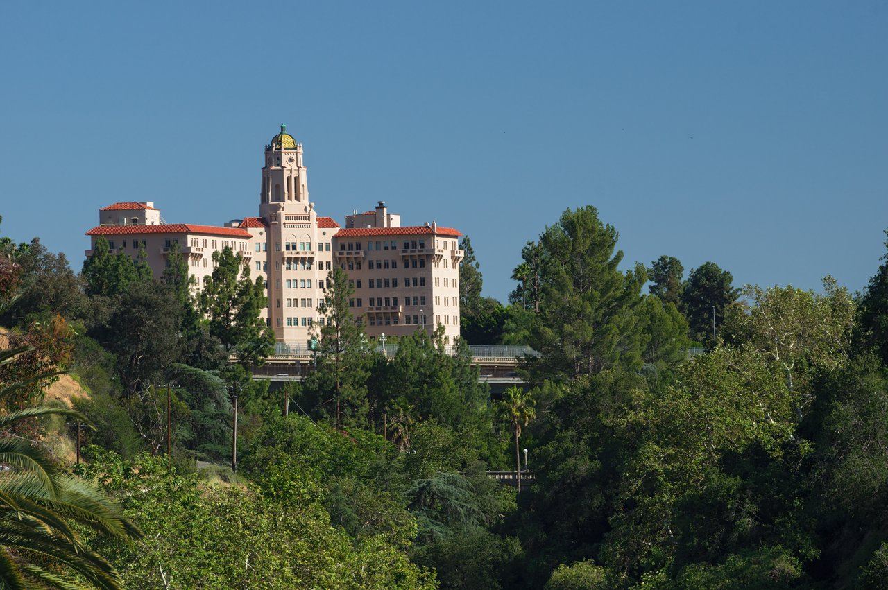 Towered building with red tile roofs rising above leafy trees in South Pasadena.