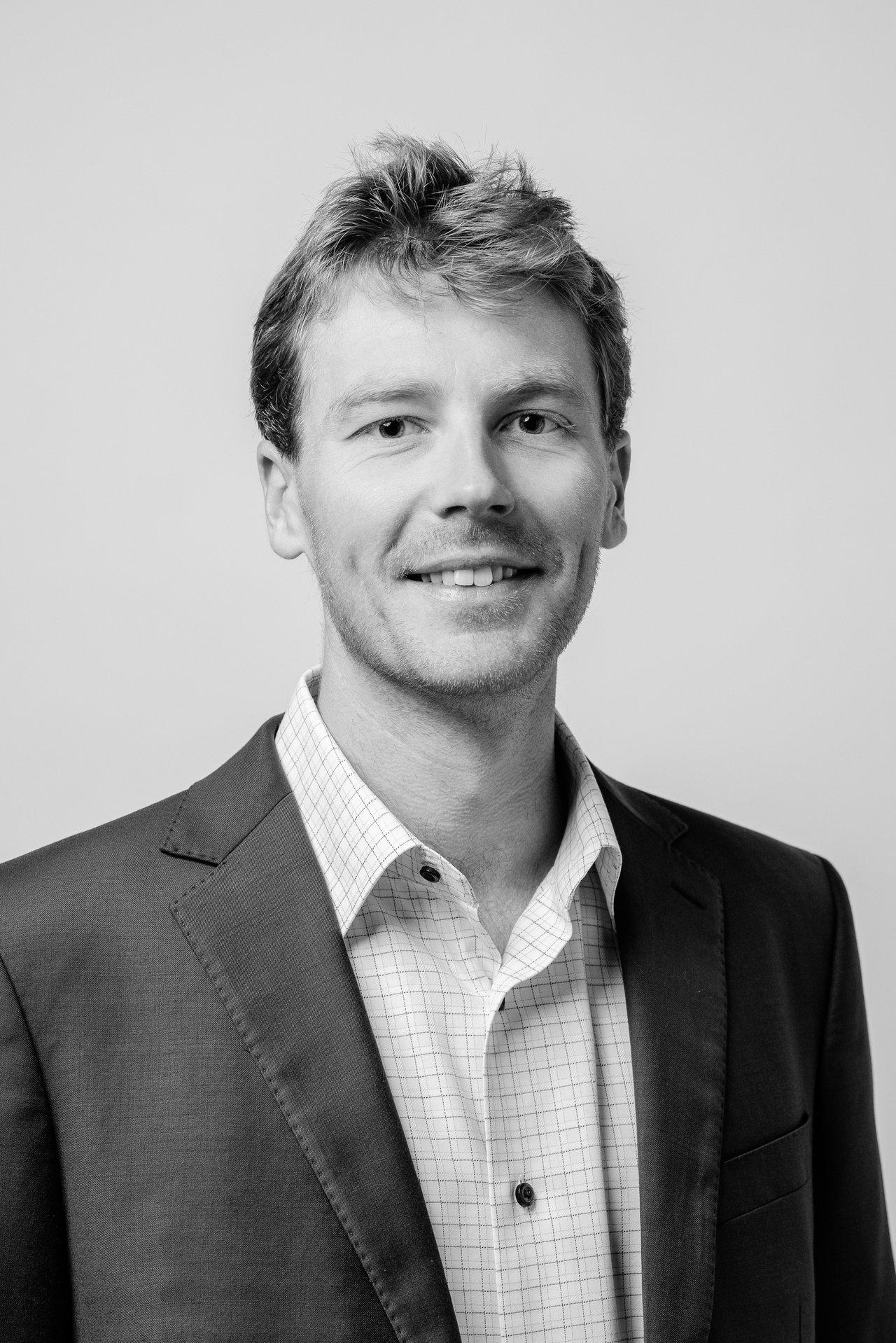 Clifford Foster smiling in a dark blazer and checked shirt.