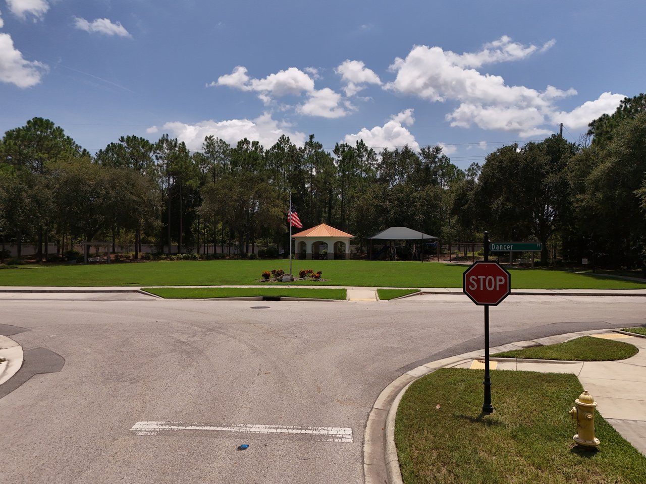 Austin Park community lawn with a pavilion, covered playground, and American flag beside the street.