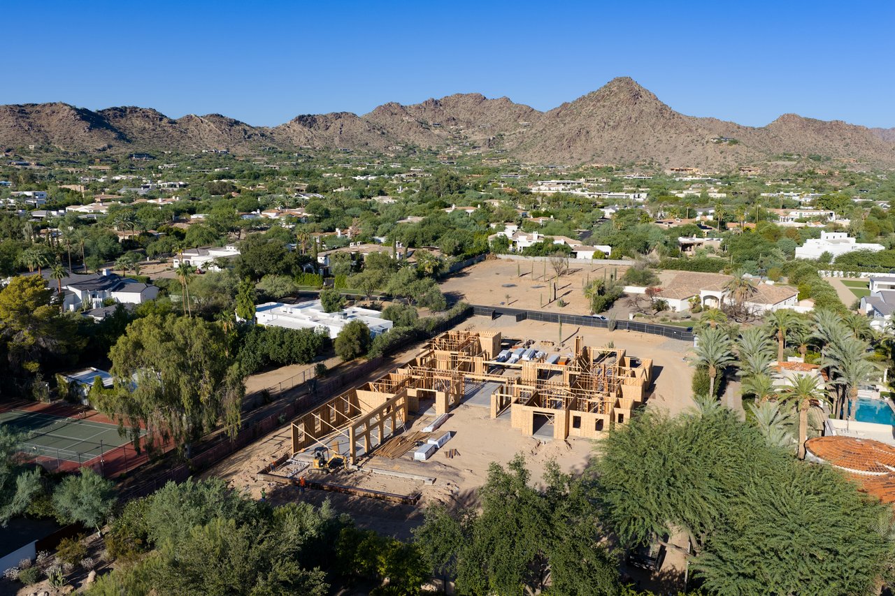Aerial view of a home construction site with mountain backdrop and surrounding desert neighborhood.