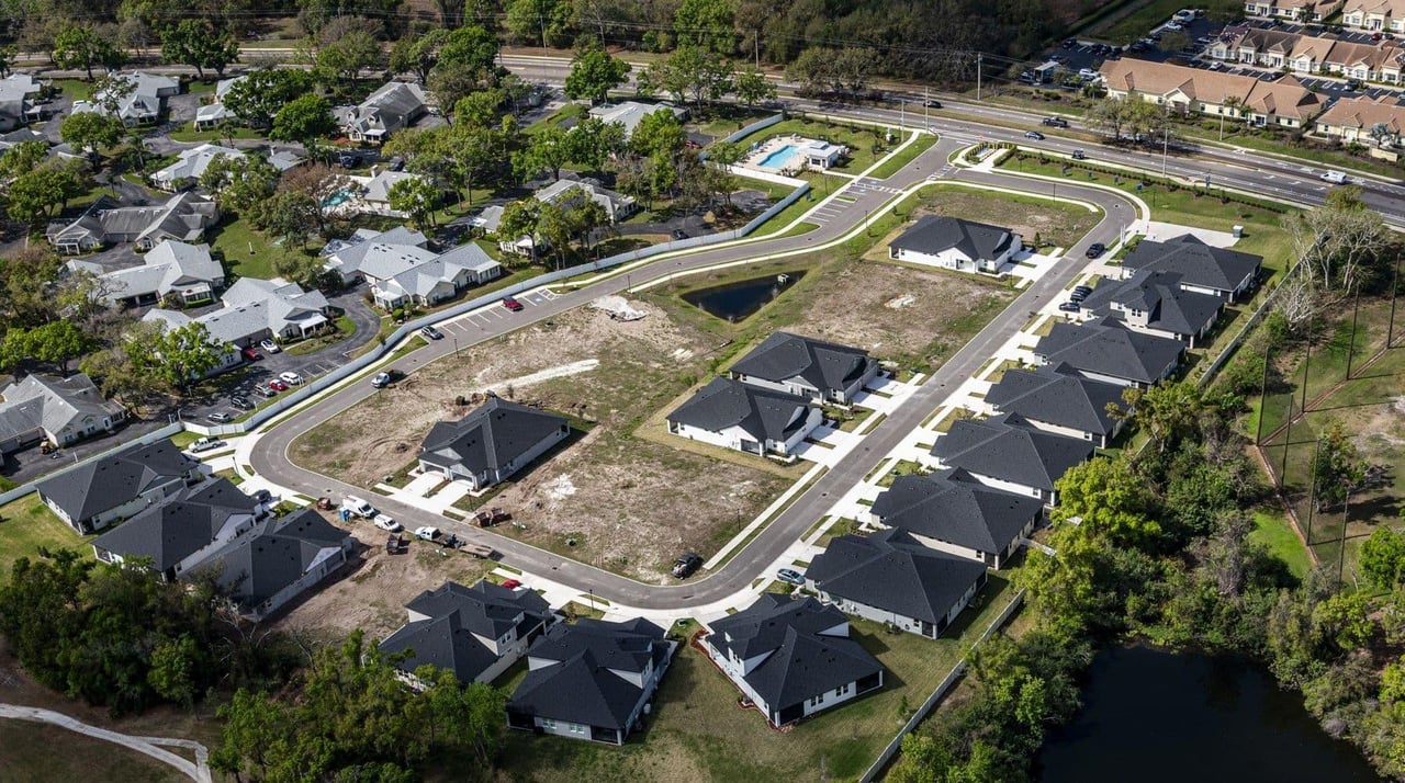 Aerial view of a residential development with new homes and cleared lots along curving streets.