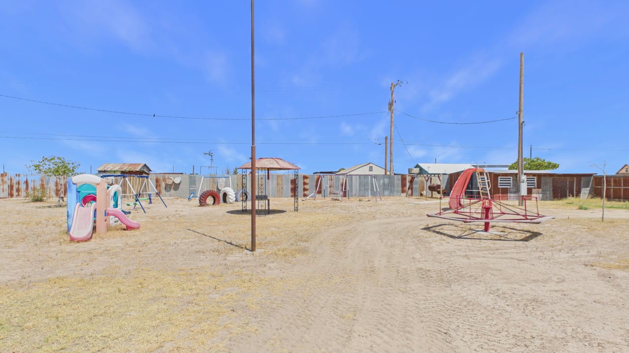 Outdoor playground with colorful slides, swings, and a red merry-go-round.