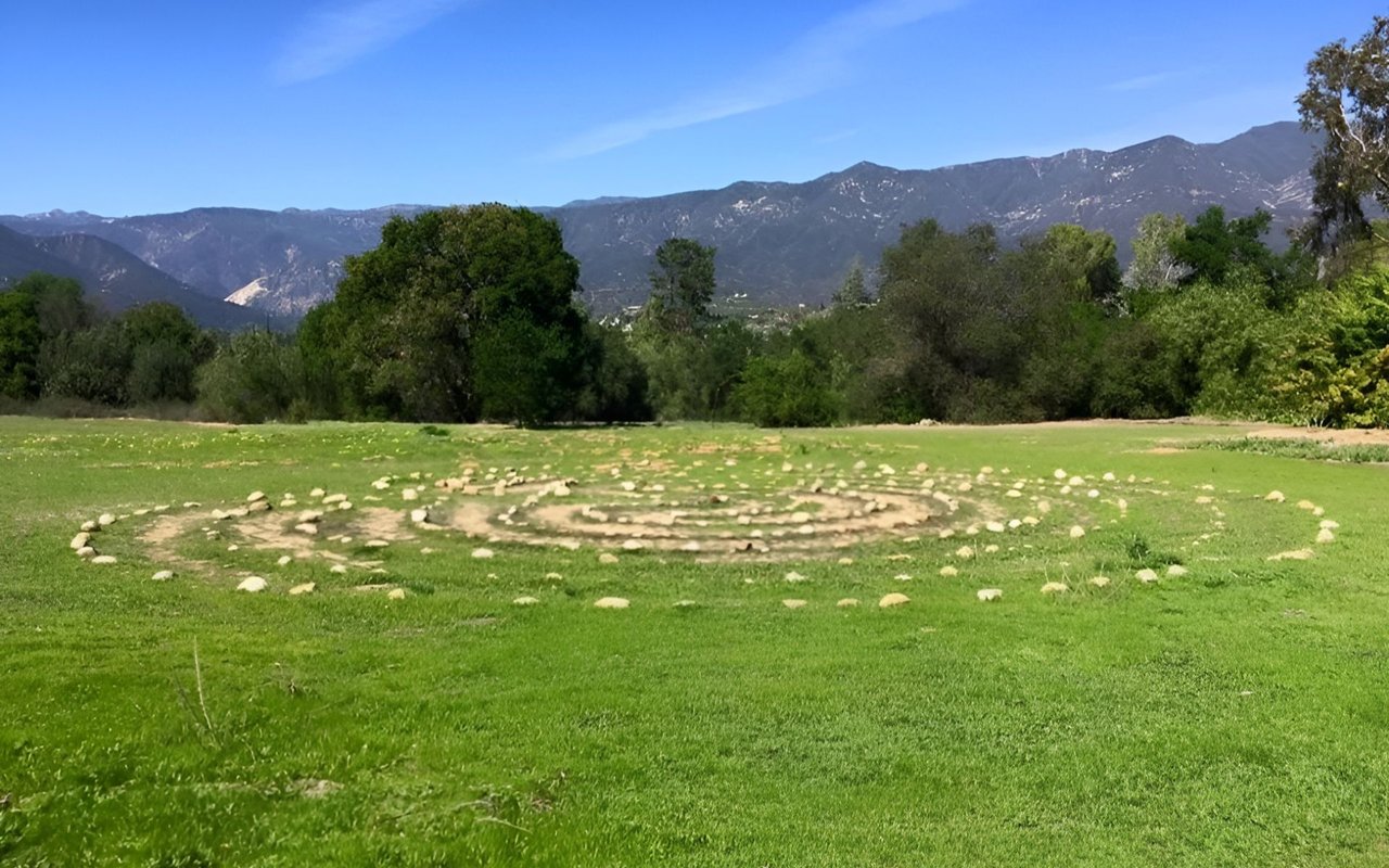 Circular stone arrangement in a green meadow with trees and mountains near Ojai.