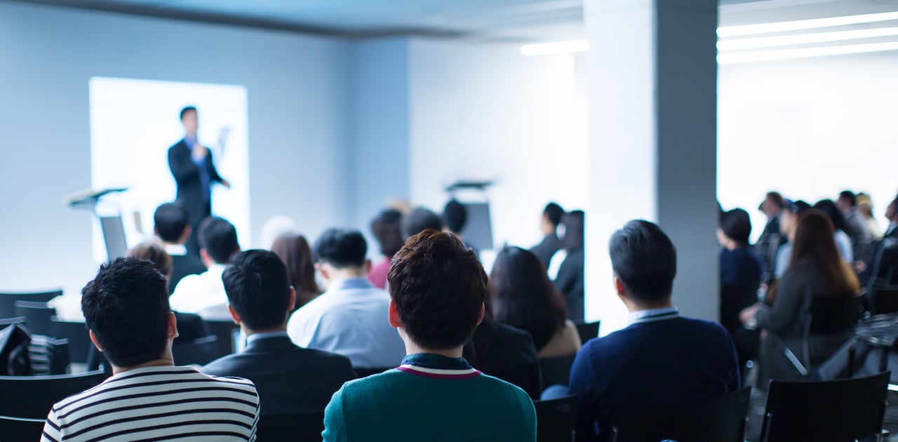 Business seminar with professional audience listening to real estate presentation.
