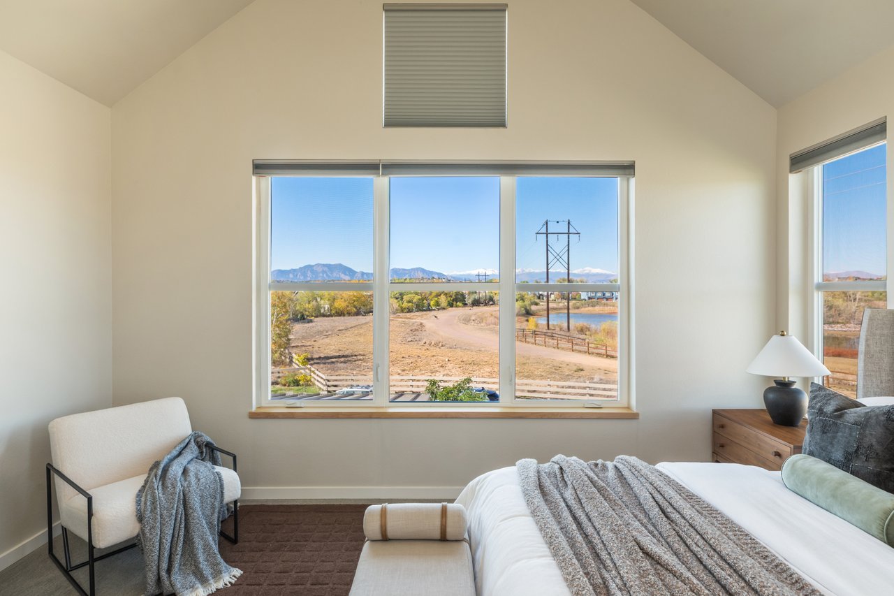 Primary bedroom window looking out to open space and mountains, with an accent chair