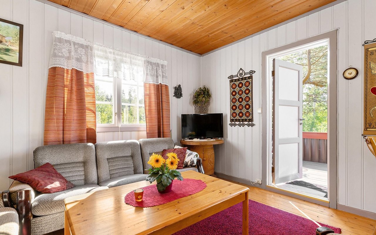 Living room with a wood-plank ceiling, gray sofa, and open door to a balcony.