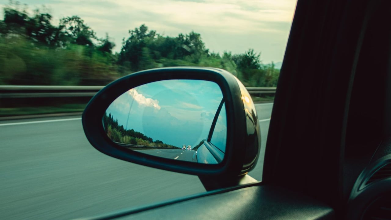 View through a car window of the side mirror reflecting a highway at dawn, like the morning drive Evans and Columbia County commuters make to Fort Gordon